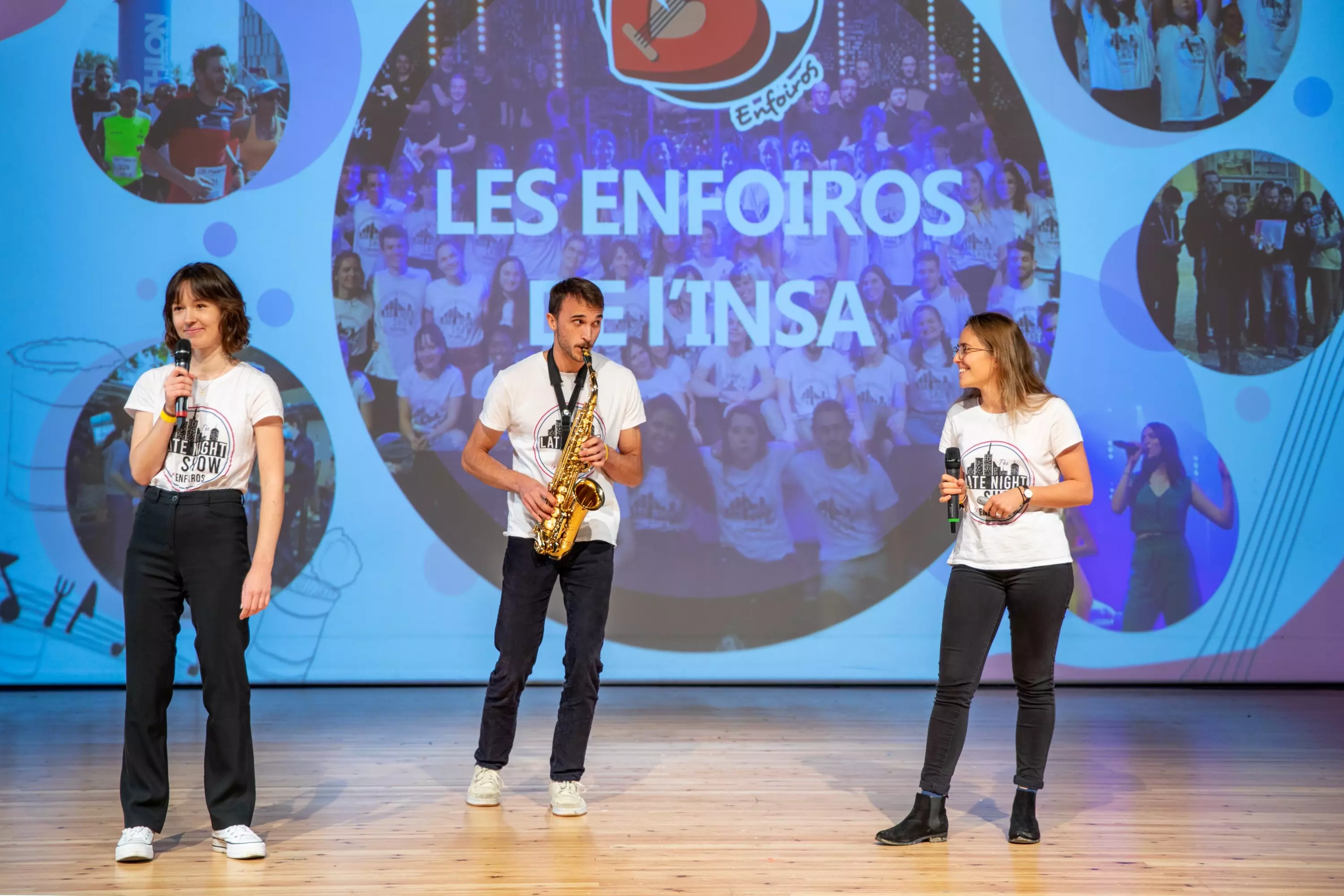 Photo du pitch de l'association Les Enfoiros de l'INSA sur scène avec sa présentation dans le fond